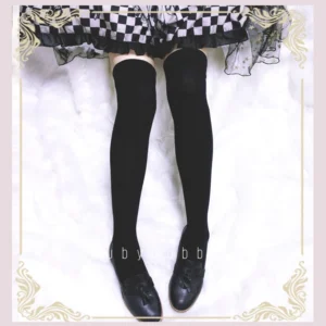 Black smooth knit over-the-knee Lolita stockings paired with black leather Mary Jane shoes and classic Lolita skirt, front overhead view, white fuzzy background