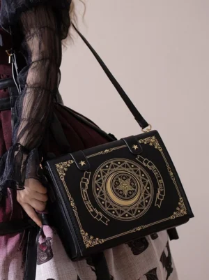 Black magic book lolita crossbody clamshell bag with gold foil celestial patterns worn as shoulder bag over gothic lolita outfit