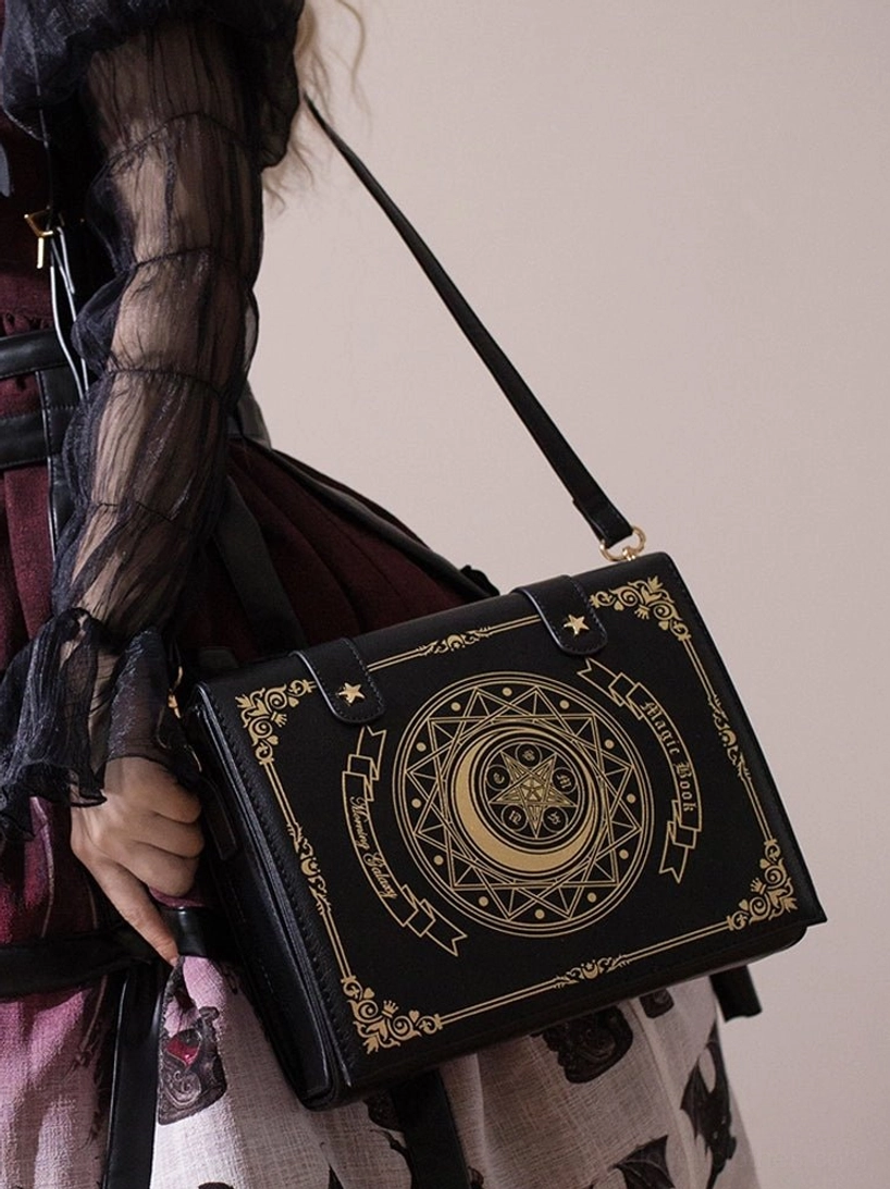 Black magic book lolita crossbody clamshell bag with gold foil celestial patterns worn as shoulder bag over gothic lolita outfit