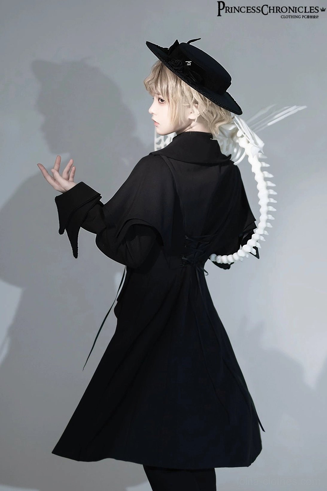 Back view of black Ouji Lolita swallowtail long vest showing extended tail hem, high standing collar, and adjustable back drawstring detail on model wearing black bow hat