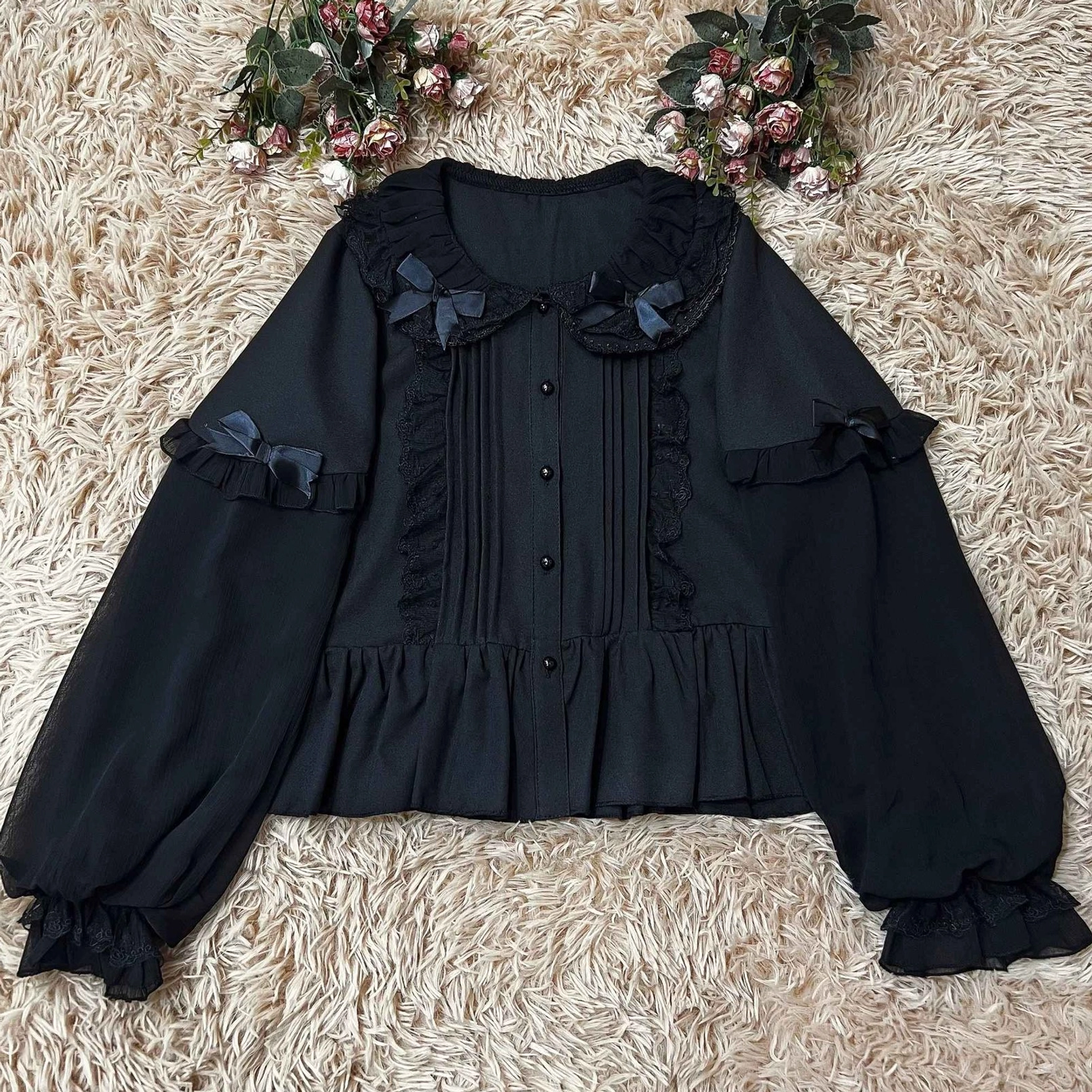 Black sweet Lolita puff-sleeve blouse with ruffled Peter Pan collar, small satin bows, front lace pintucks and ruffled cuffs - flat overhead display on fluffy white fur background