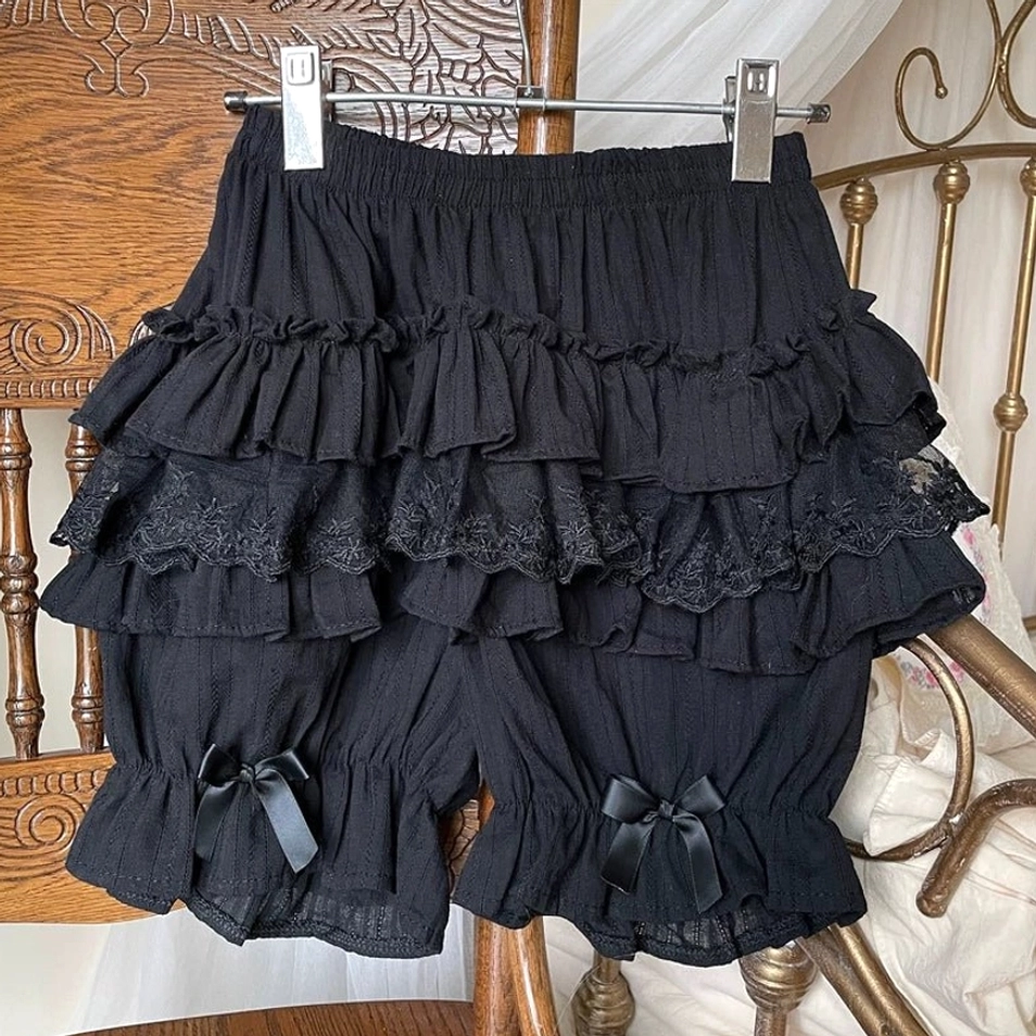 Black sweet lolita cotton bloomers displayed hanging vintage wooden chair clothes hanger solid black all-over ruffle layers satin bows leg cuffs front view