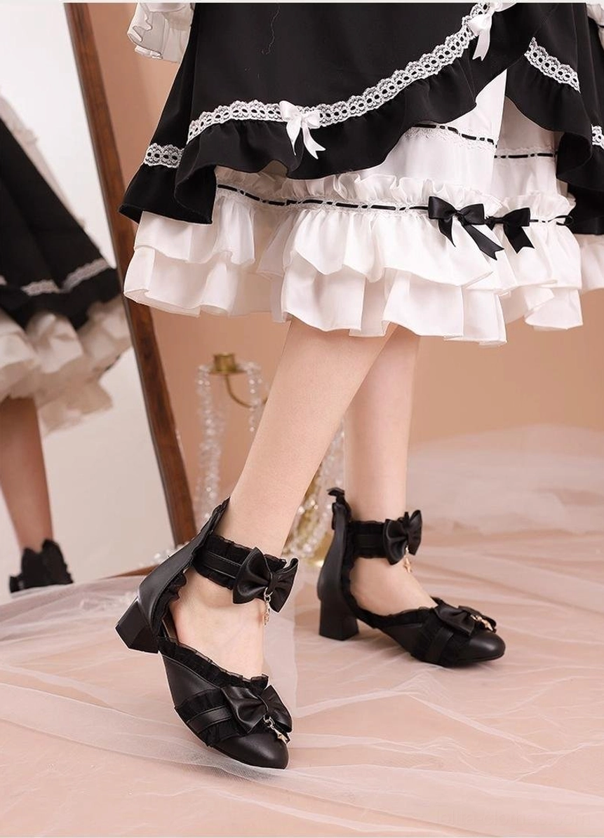 Black Sweet Lolita Mary Jane shoes back low angle view showing star charm bow, ruffled ankle straps, back zipper closure on model in black-white frilled lolita skirt