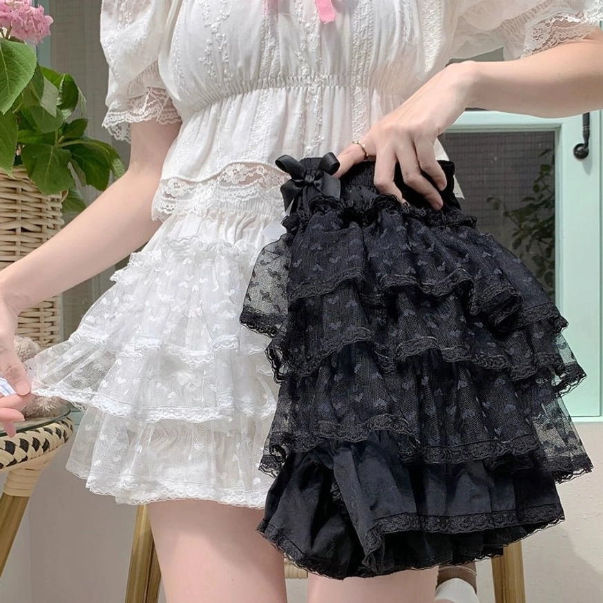 Black tiered ruffled Lolita bloomer shorts with sheer mesh layered fabric and lace trim worn in close-up side holding view in dining patio setting