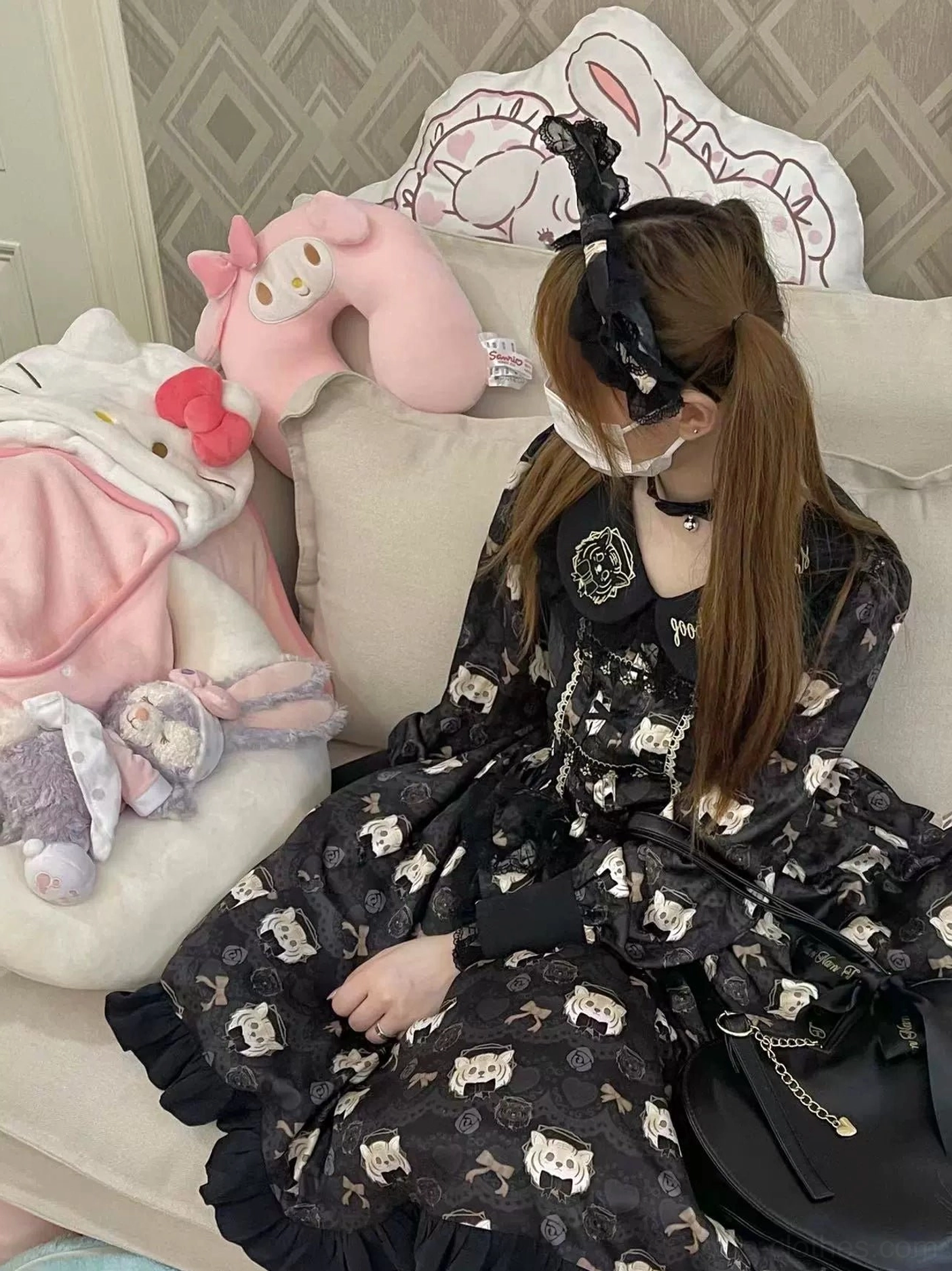 Black tiger print lolita OP dress side sitting pose on plush toy filled sofa showing embroidered collar detail ruffled cuffs all-over tiger pattern with leather crossbody bag