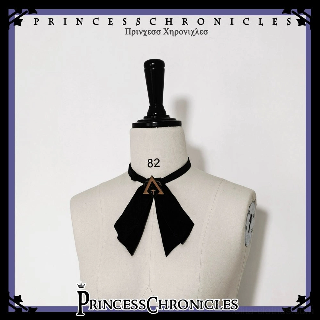 Black velvet bow necktie with triangular gold metal ornament buckle detail, close-up display on dress form, Ouji Lolita formal accessory, studio showcase framing
