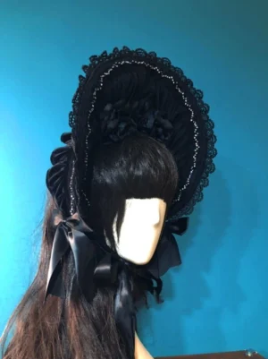 Black velvet gothic lolita bonnet left side profile showing gathered velvet crown, delicate beaded lace brim trim and satin chin bow detail