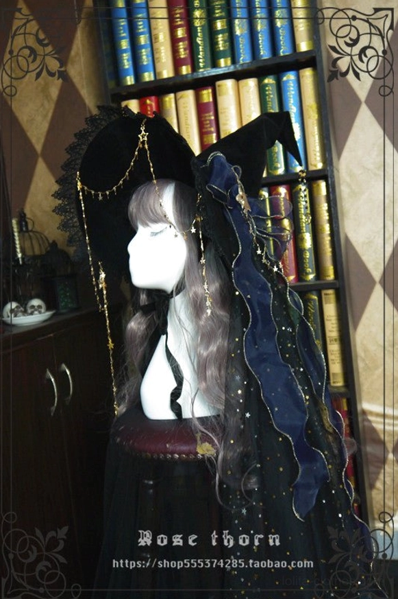 Black velvet lolita witch hat with navy star-patterned sheer veil and gold chain trim, displayed on mannequin with grey wig in vintage study setting