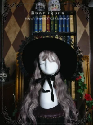 Black velvet pointed witch hat worn on mannequin with curly brown wig, featuring lace-trimmed brim and black ribbon tie in retro study setting - lolita gothic headdress front view