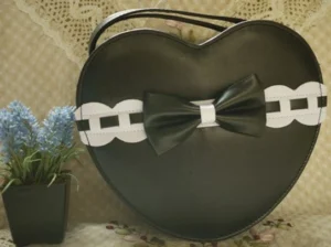Black and white heart-shaped lolita shoulder bag with bow and chain trim vintage lace backdrop