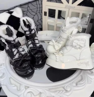Black and white patent leather lolita snow boots with plush collar detachable bow pom-pom accents flat lay display decorative mirror tray cozy indoor