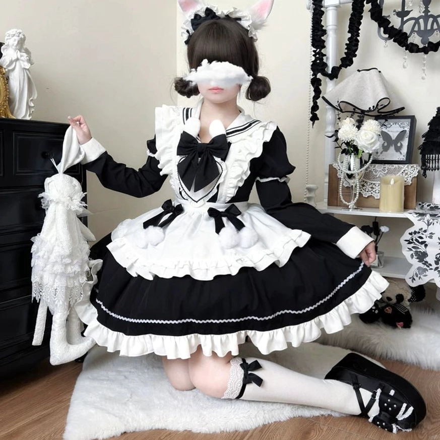 Model wearing black and white maid lolita dress in kneeling front pose with cat ear hairpin, white stockings and black leather shoes, ruffled apron and front bow visible