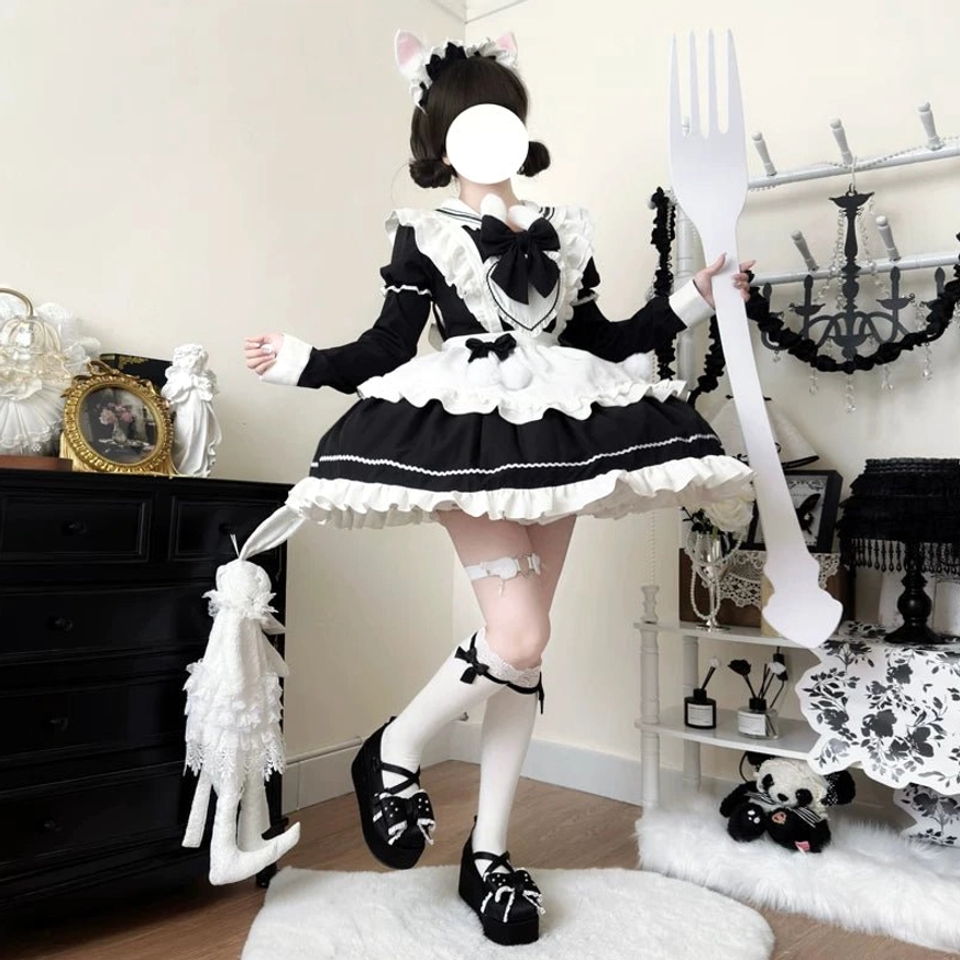 Model in black and white maid lolita dress standing with giant fork prop, cat ear hairpin, leg-strap stockings, lace-up Mary Jane shoes, contrast color blocking and ruffled trims visible