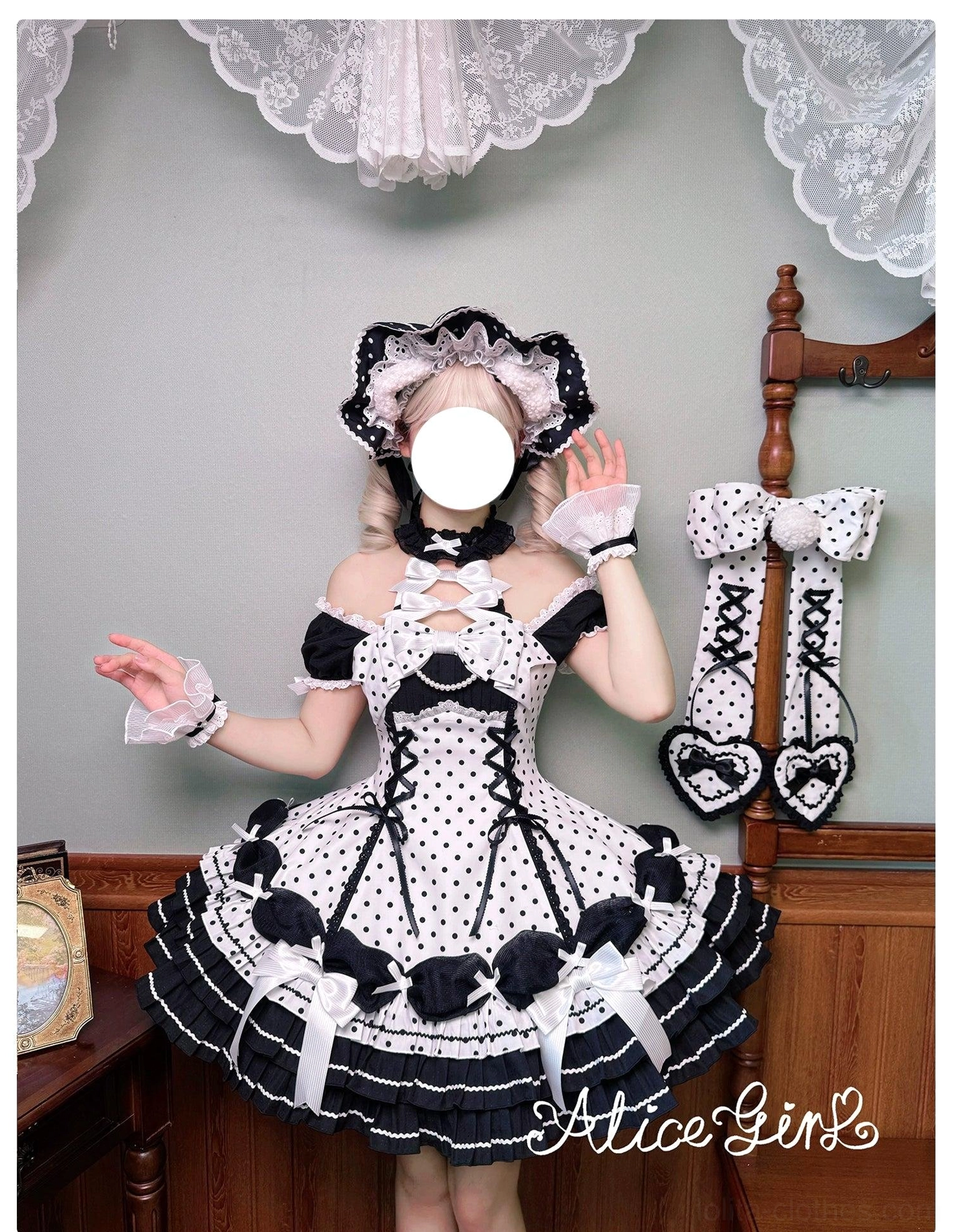 Black and white polka dot maid-style Lolita dress model wearing with matching bonnet cuffs and detachable leg bows lace trim