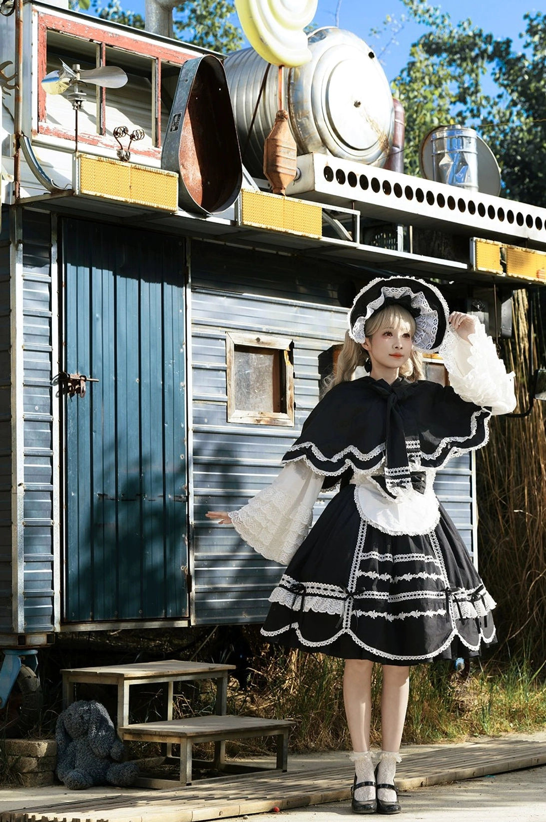 Classic black and white lolita dress with rabbit ear cape full body outdoor shot model retro caravan background white lace trims maid-style apron structured ruffled