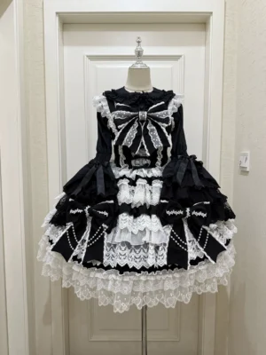 Black and white Sweet Lolita JSK ensemble with contrast lace trim displayed on mannequin featuring thick lace ruffles and large front pearl bow decoration