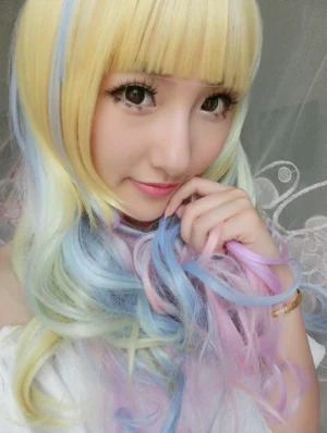 Blonde to blue to pink gradient long curly Lolita wig with blunt bangs shown from three-quarter angle on white mannequin head, displaying color transition from light blonde roots through oceanic blue mid-tones to blush pink ends, loose bouncy curls