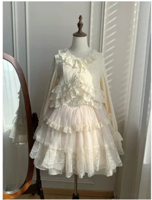 Beige lolita jumperskirt dress with pleated bodice, layered lace ruffles and multi-tiered tulle skirt, full front view on dress mannequin with floor mirror