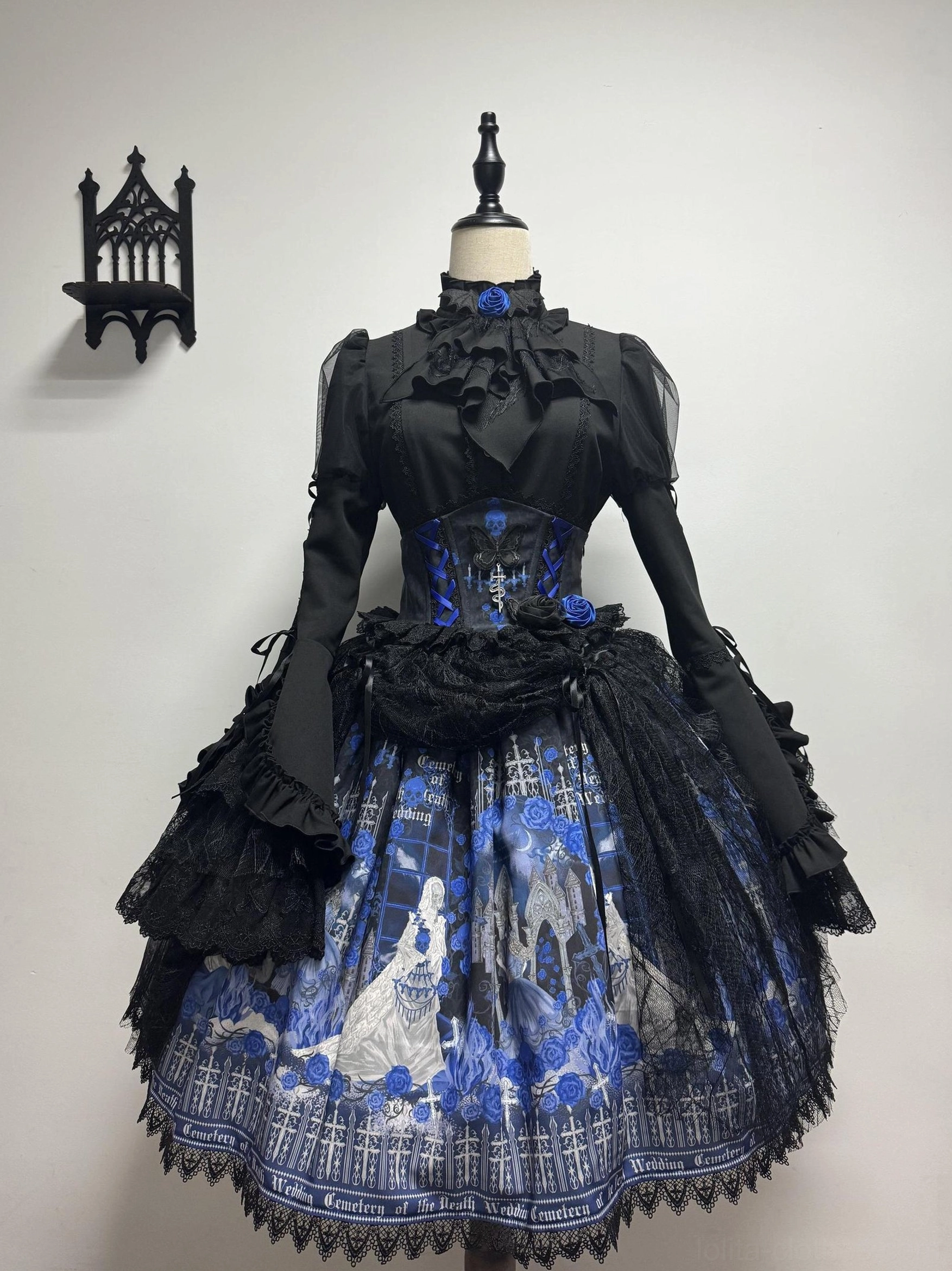 Blue Blood Wedding Gothic Lolita complete dress set front three-quarter view - ruffled stand collar blouse, corset waist, printed skirt with black lace bustle accessory, gothic wall backdrop
