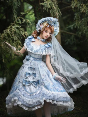 Blue floral wedding lolita JSK dress worn by model in forest setting, featuring tiered ruffled shoulders with large bows, layered lace hem, front decorative bows, jacquard vintage floral print fabric, matching bonnet and pearl veil