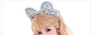 Close-up detail of blue gingham cat ear lolita KC headband with delicate white lace trim and satin bow on blonde model wearing sweet lolita fashion