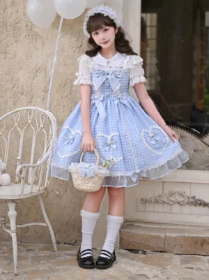 Young girl wearing blue gingham sweet lolita JSK dress with short-sleeve lace blouse and peter pan collar, holding straw flower basket, seated on vintage white metal chair in stone courtyard