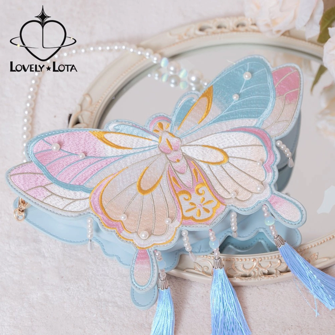 Blue and pink gradient Chinese Qi Lolita butterfly handbag with golden embroidery and matching blue tassels on vintage makeup mirror