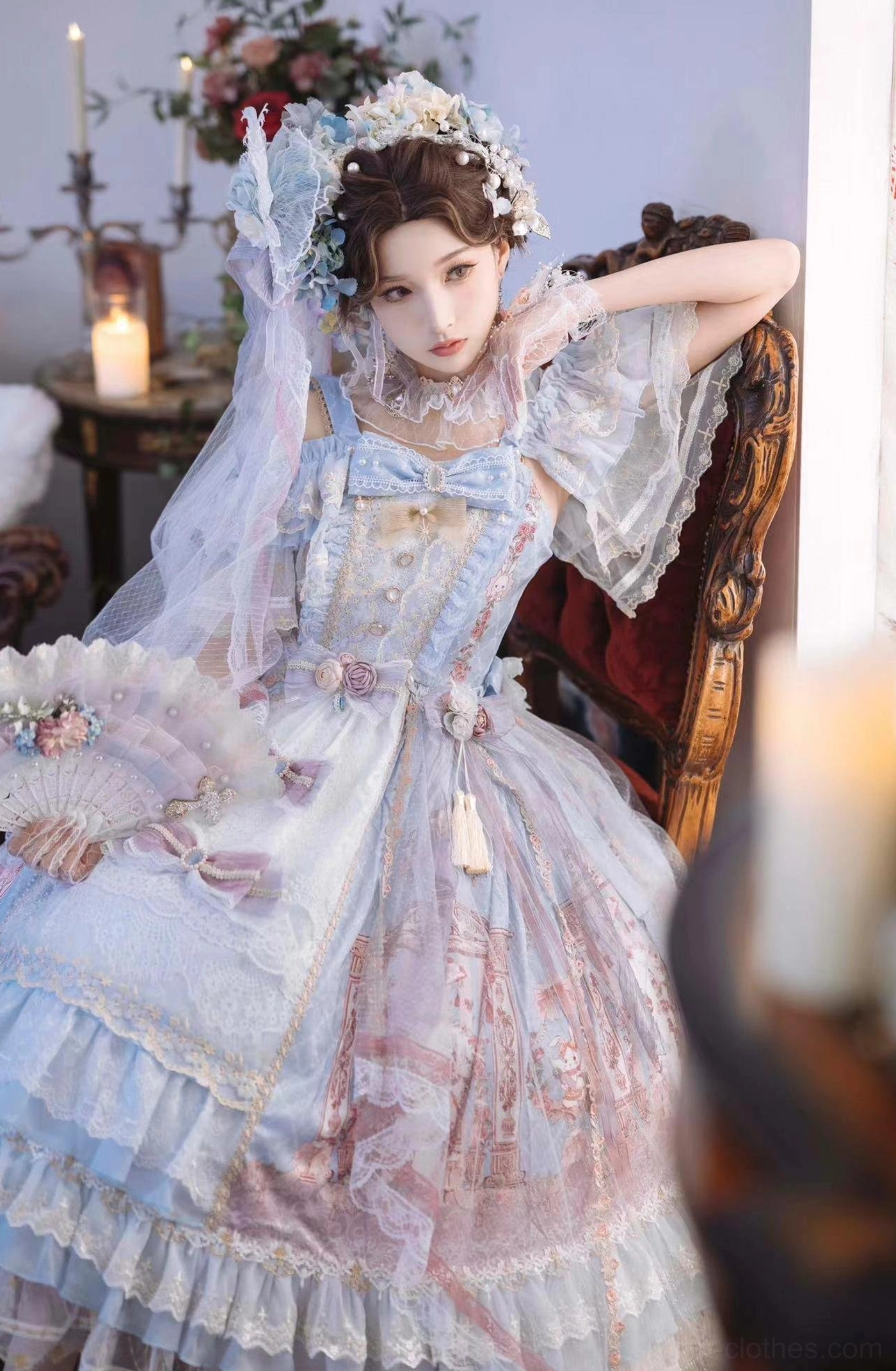 Blue-pink gradient wedding Lolita JSK dress with short flutter lace sleeves and bow front bodice, model sitting on vintage wooden chair holding lace fan