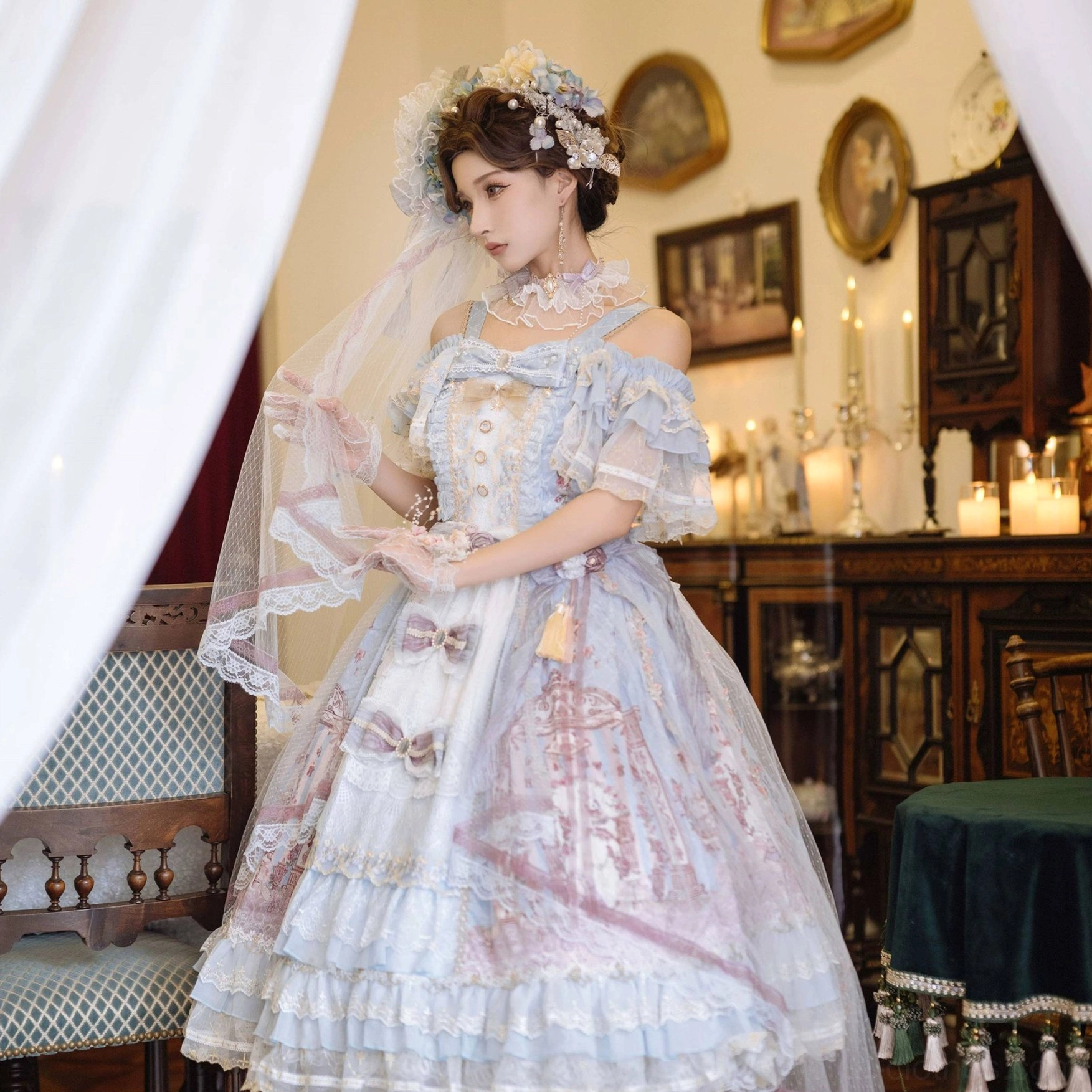 Blue-pink vintage wedding Lolita JSK dress with off-shoulder ruffled lace sleeves and tiered layered skirt with vintage print, model with floral hair ornaments in candlelit dining room
