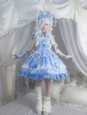 Blue plaid sweet lolita jumper skirt JSK dress front full-body single model view featuring blue-and-white checkered fabric with layered ruffled lace trim and matching arm sleeves, white stockings and leg warmers, indoor bedroom sheer curtain backdrop
