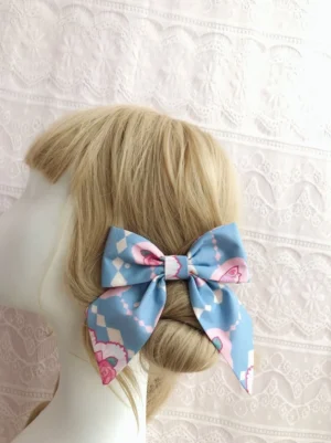 Blue sweet lolita bow hair clip with long dangling ribbon tails and rose-print details worn on styled blonde bun, rear view showcasing argyle and floral print design
