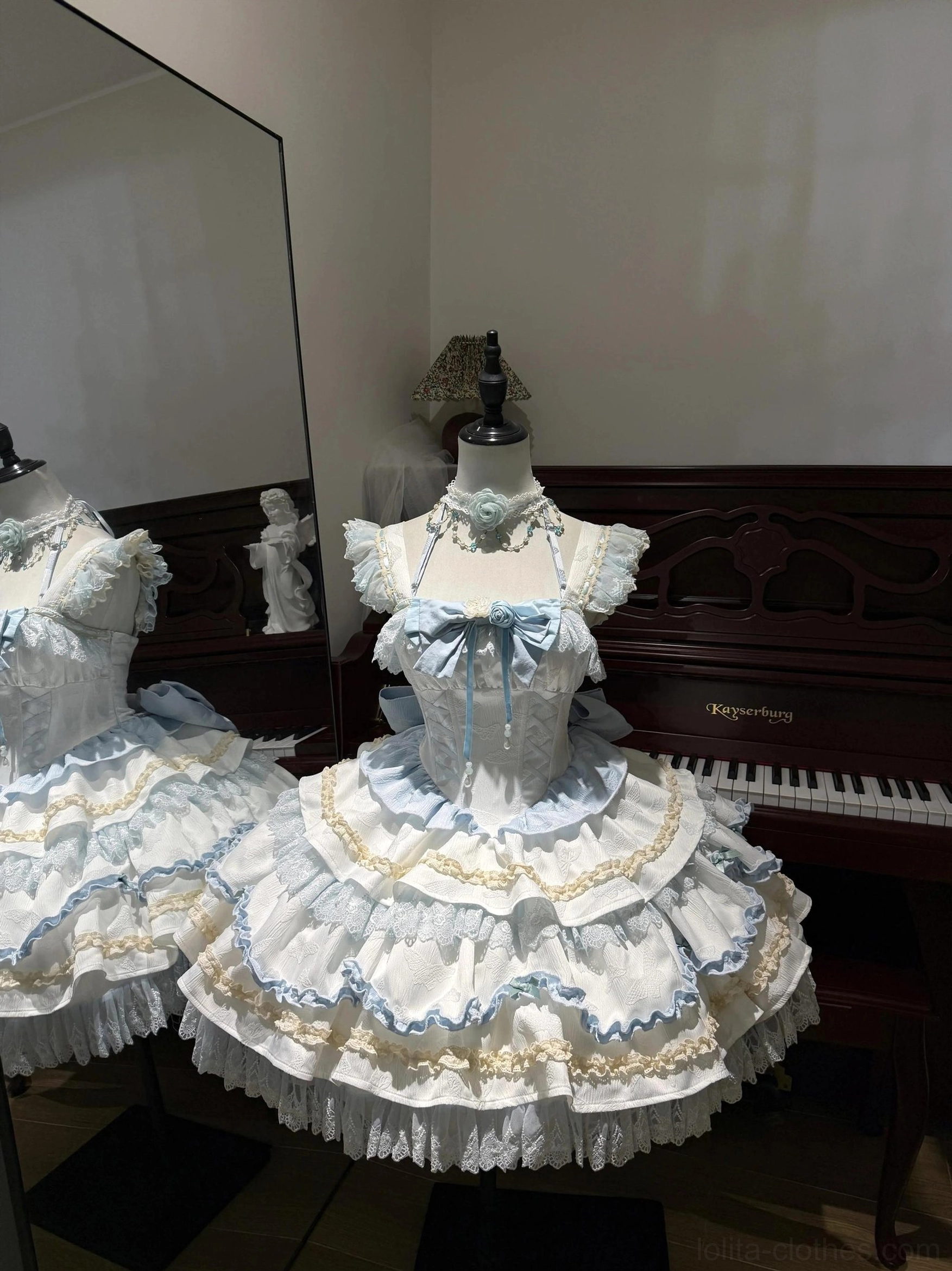 Blue and white sweet lolita jumper skirt front view with ruffled shoulder straps blue bow tiered lace trimmed skirt floral neck accessory mirrored backdrop