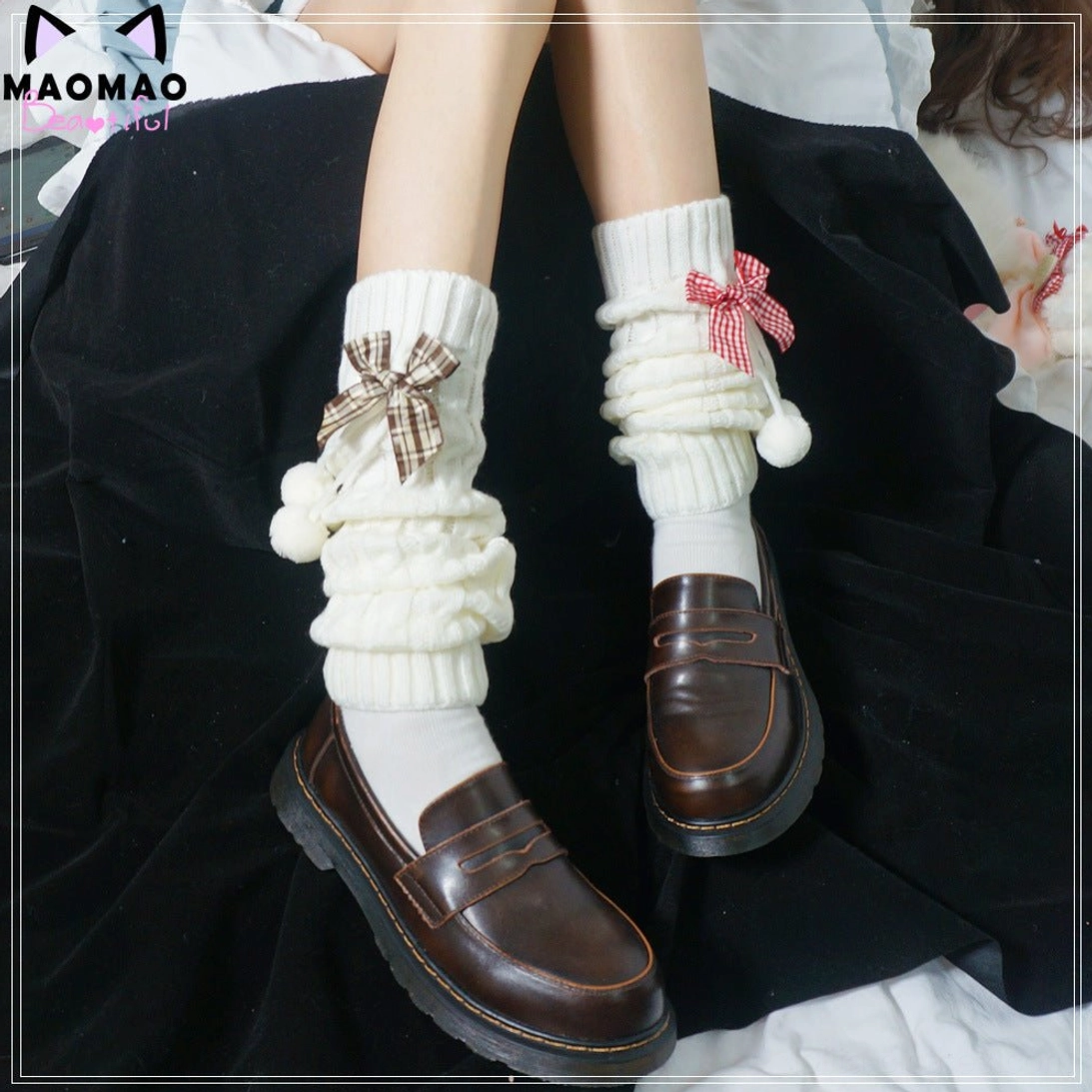 Bow decorated knitted leg warmers front view worn with brown leather loafers white socks and JK school uniform featuring twisted knit texture detachable plaid bows pom-pom charms