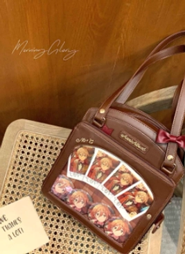 Brown lolita itabag flat lay top-down view showing transparent display slot with anime cards red bow accent heart zipper