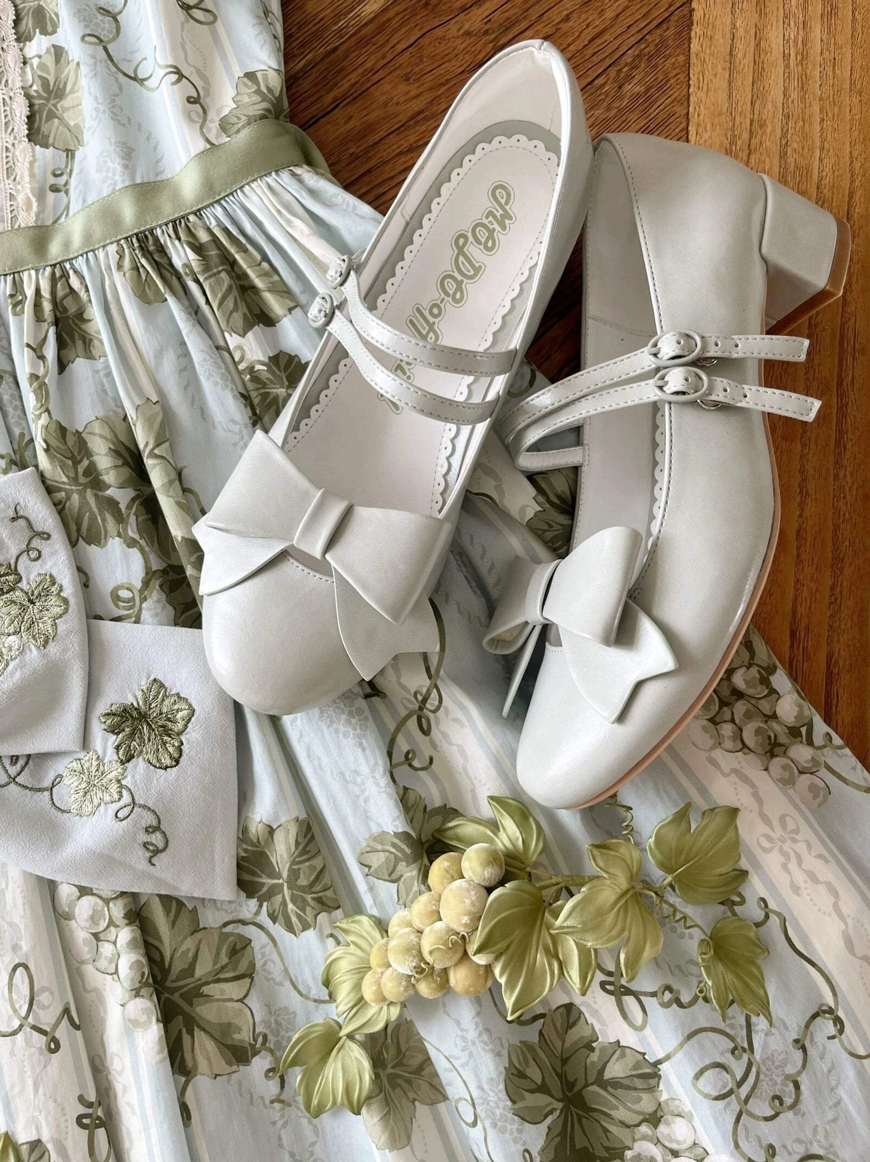 Brown Lolita Mary Jane shoes with glossy patent leather finish low block heel ankle strap bow displayed overhead flat lay vintage wooden background styling photography