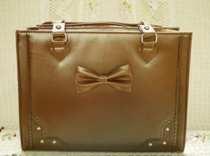 Brown structured Lolita tote handbag with front bow, top zipper closure, rivet details, and large capacity