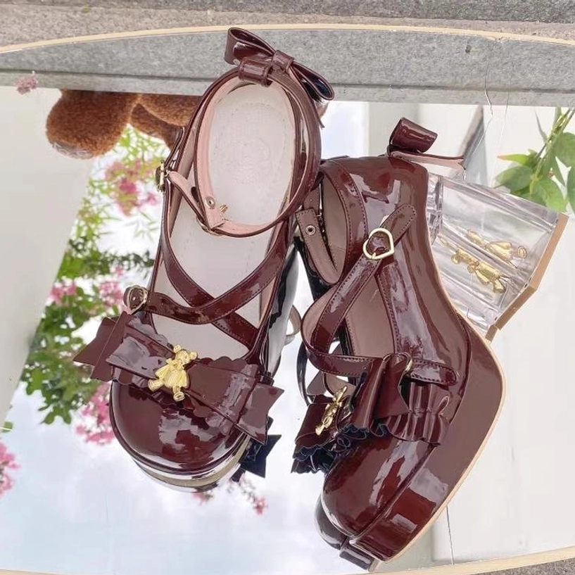 Burgundy brown sweet lolita platform heels side close-up shot, green foliage and small teddy bear prop background, patent leather finish, ankle strap with bow, gold bear charm, clear block heel, warm autumn tone