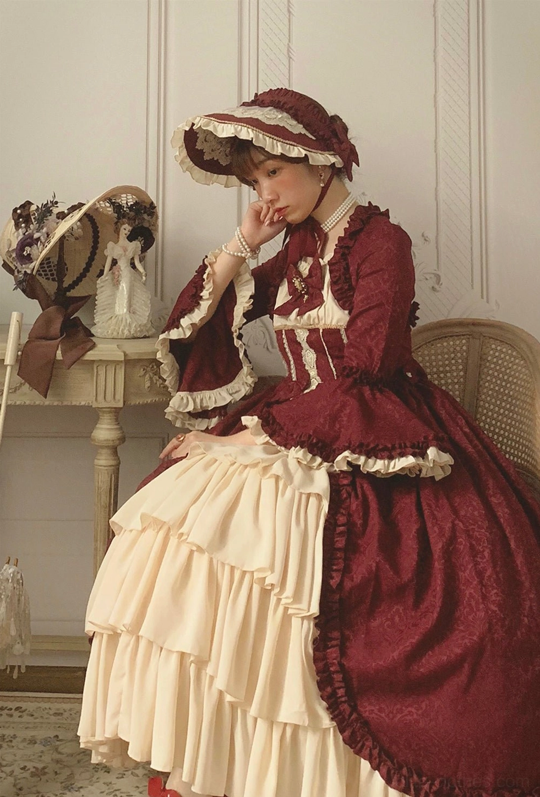 Full-body model wearing burgundy and cream Lolita bonnet gown set vintage European room styling