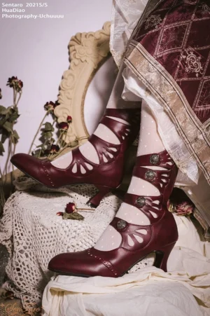 Burgundy floral hollow-out Mary Jane Lolita ankle boots with wine glass heel and metal buckles displayed on vintage-style table with lace and dried flowers