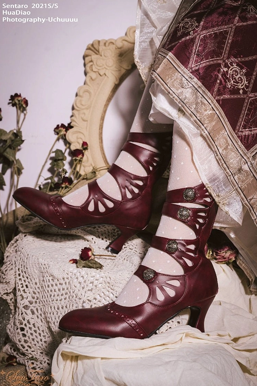 Burgundy floral hollow-out Mary Jane Lolita ankle boots with wine glass heel and metal buckles displayed on vintage-style table with lace and dried flowers