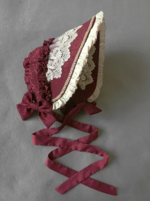Burgundy vintage Lolita adjustable bonnet flat lay with embroidered lace and ivory ruffle trim headdress