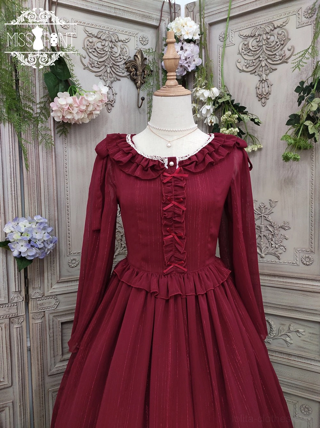 Burgundy lolita one-piece dress with ruffled crew neckline, dimensional ruffled waist trim, and full pleated midi skirt featuring ruffled hemline, crafted in sheer striped chiffon, displayed on form against vintage ornate wall