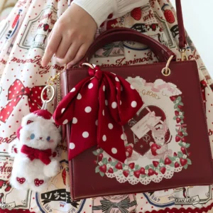 Burgundy wine red square lolita handbag with polka dot bow and rabbit print sitting on strawberry print sweet lolita dress top view close-up