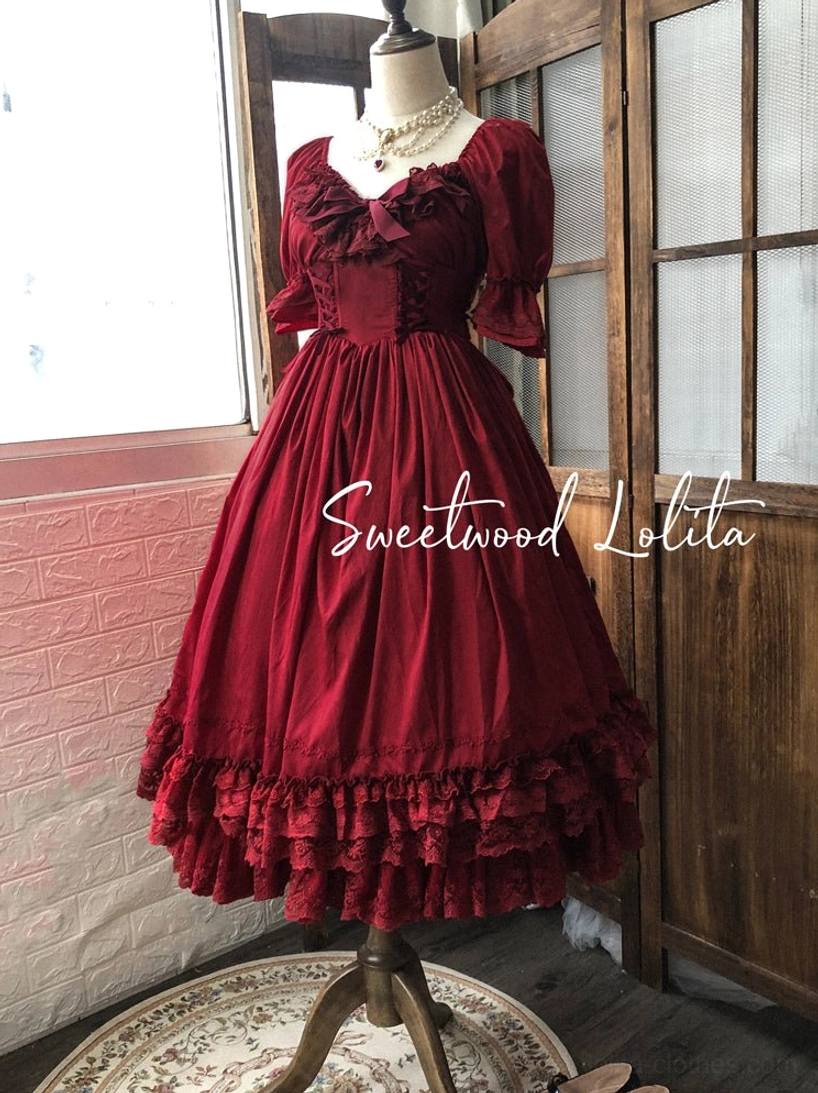 Burgundy French Lolita OP dress displayed on dress form, puff sleeves, chest bow collar and multi-layer lace ruffled hem in vintage indoor door setting