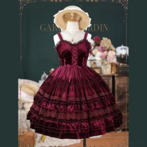 Elegant burgundy velvet Lolita JSK jumper skirt with lace corset bodice, front view showcasing full ruffled skirt and embroidered waist details, paired with straw hat accessory