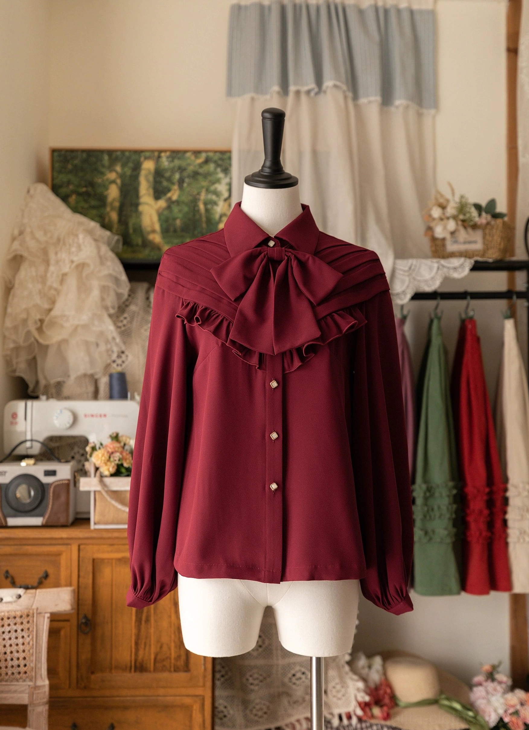 Burgundy vintage Lolita bow blouse with ruffled yoke and statement satin bow tie displayed on dress mannequin, showing front full view in retro boutique studio setting with puff sleeves and button closure