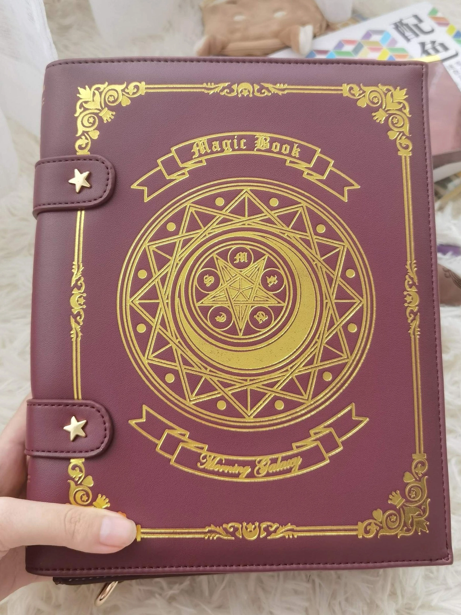 Burgundy wine red magic book themed lolita crossbody bag front flat lay with gold foil embroidery and star buckle straps on fur background