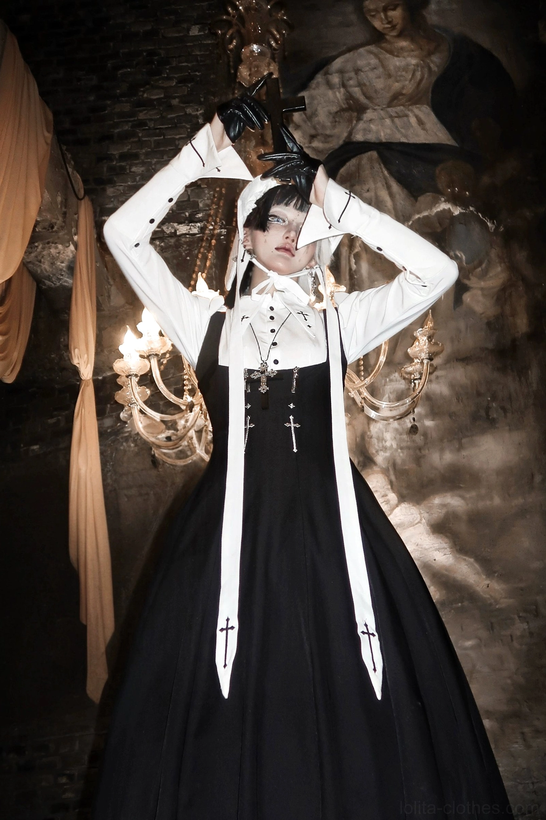 Low-angle full-body front view of bust-supporting gothic lolita JSK set with hands raised, fitted bust silhouette and cross-embroidered decorative sashes
