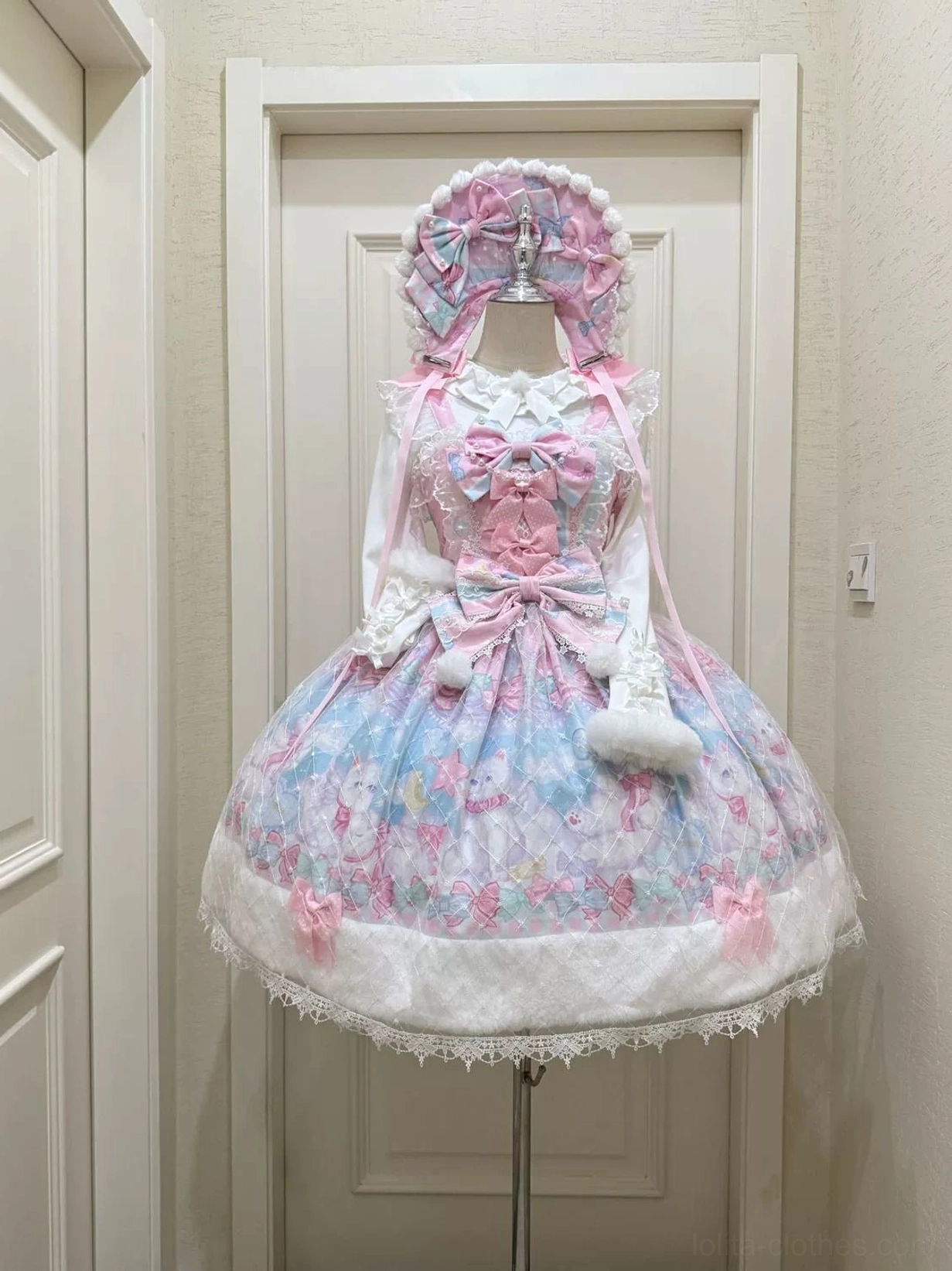 Pastel pink kitten print lolita JSK dress full skirt faux fur trim lace hem coordinating bonnet capelet front mannequin wooden door backdrop
