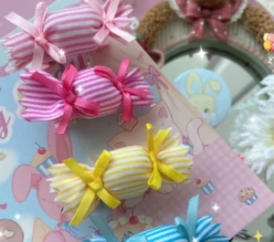 Pink yellow blue candy themed striped hair clips and brooches flat lay display coordinated ribbon bows sparkly effects bunny theme card